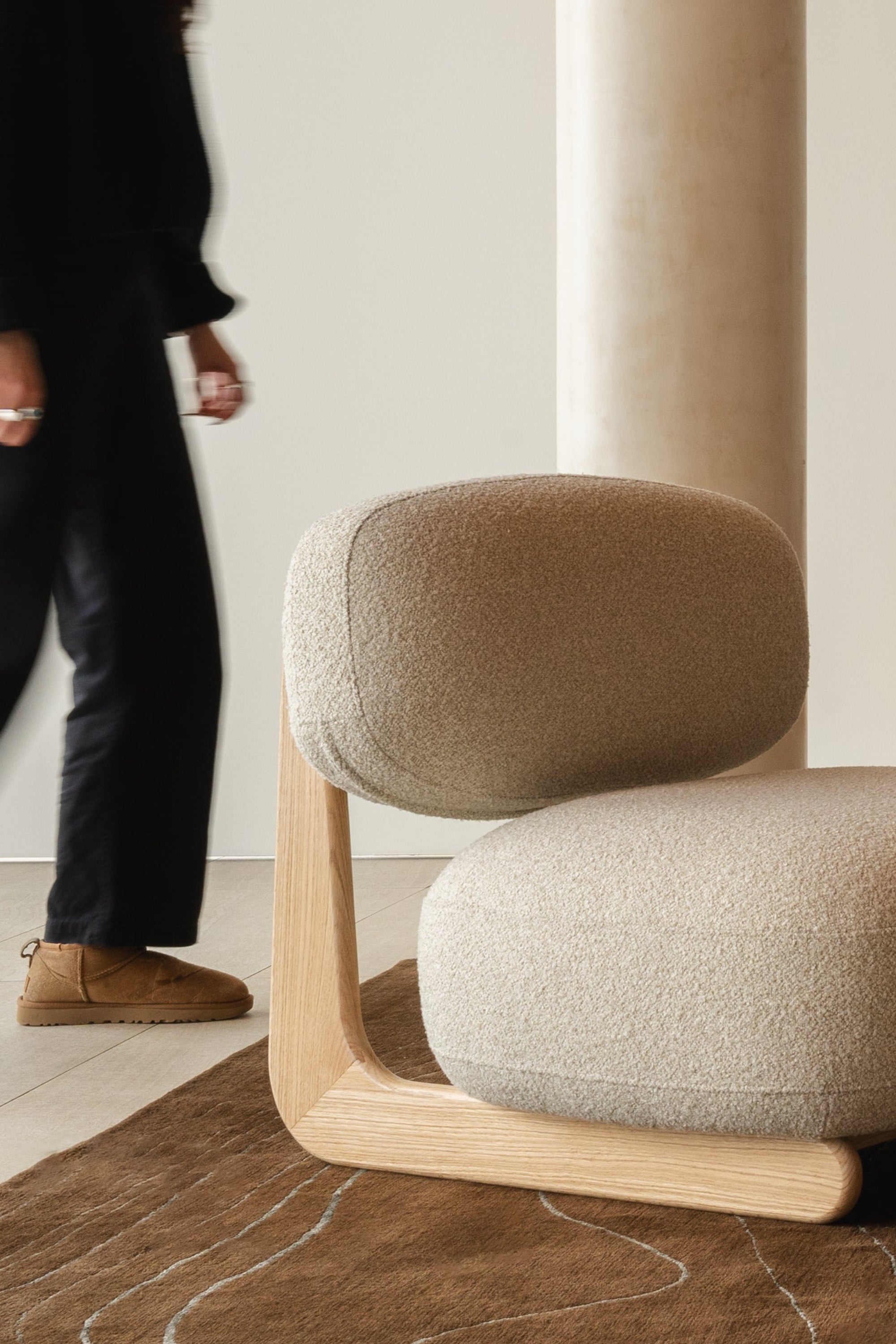 Mieux Sable cream lounge chair in a modern living room, with a person walking nearby