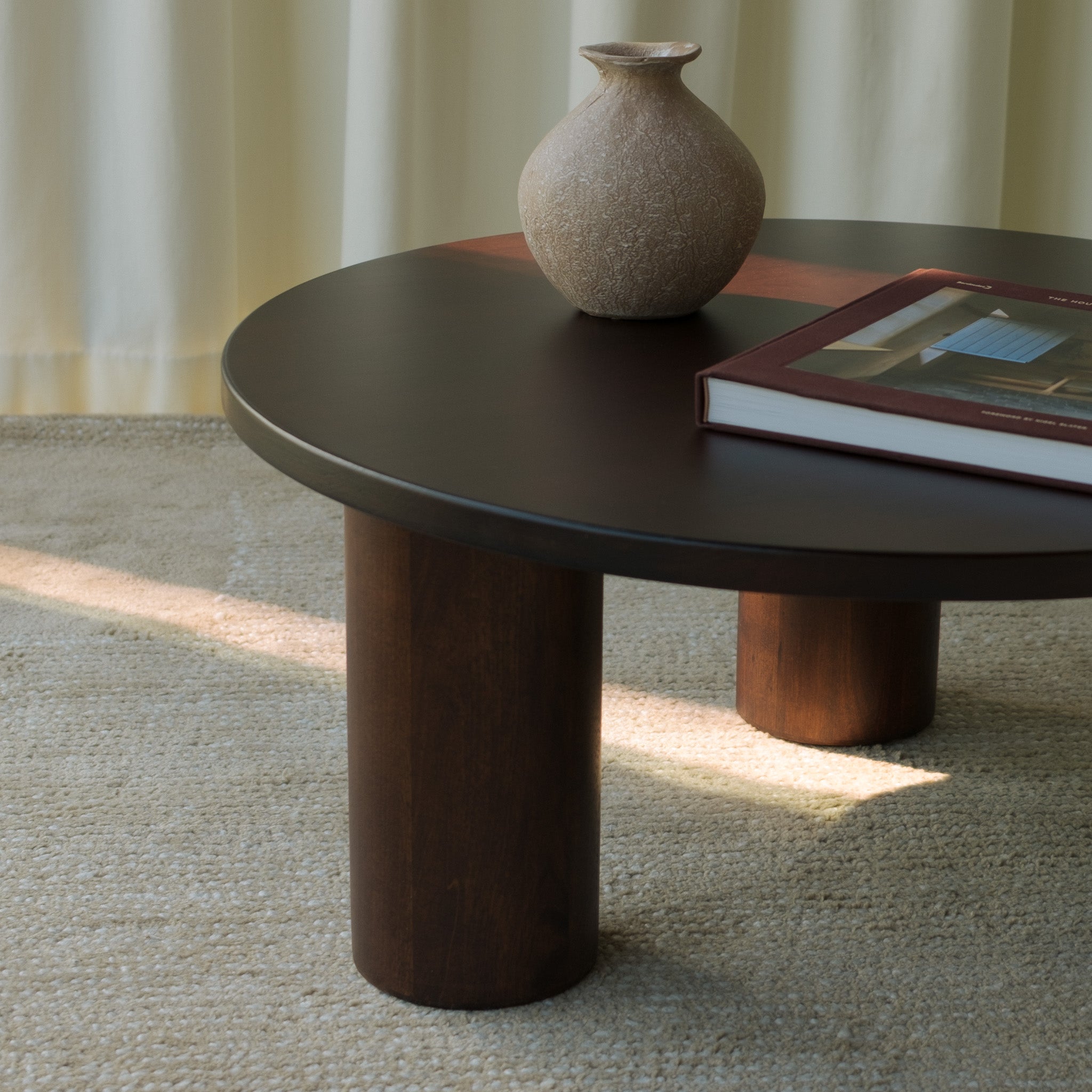 Gami solid walnut coffee table detail showing solid wood cylinder chunky legs, ceramic vase and book on top