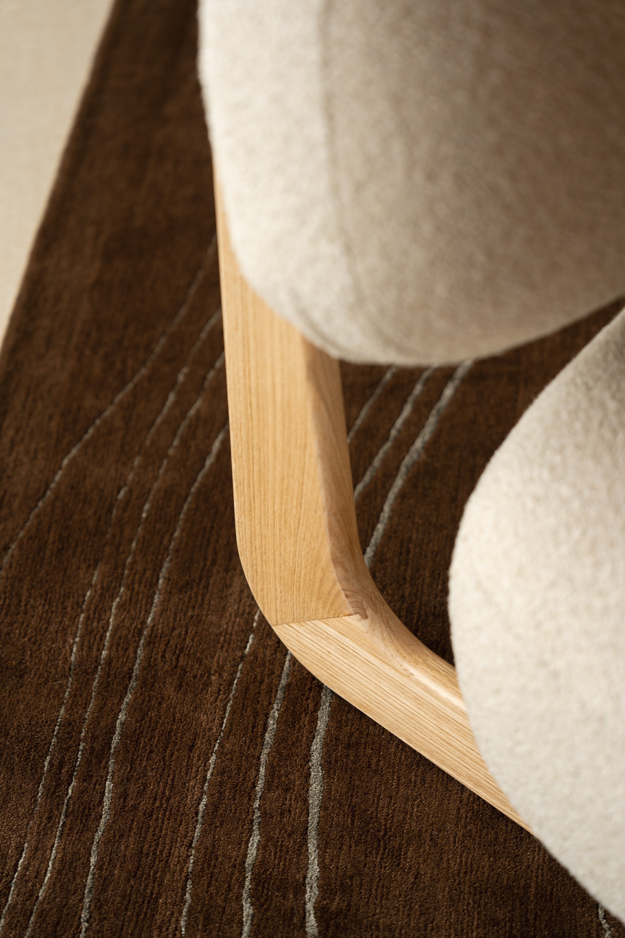 Close-up of Mieux Sable lounge chair in cream fabric on a modern brown rug